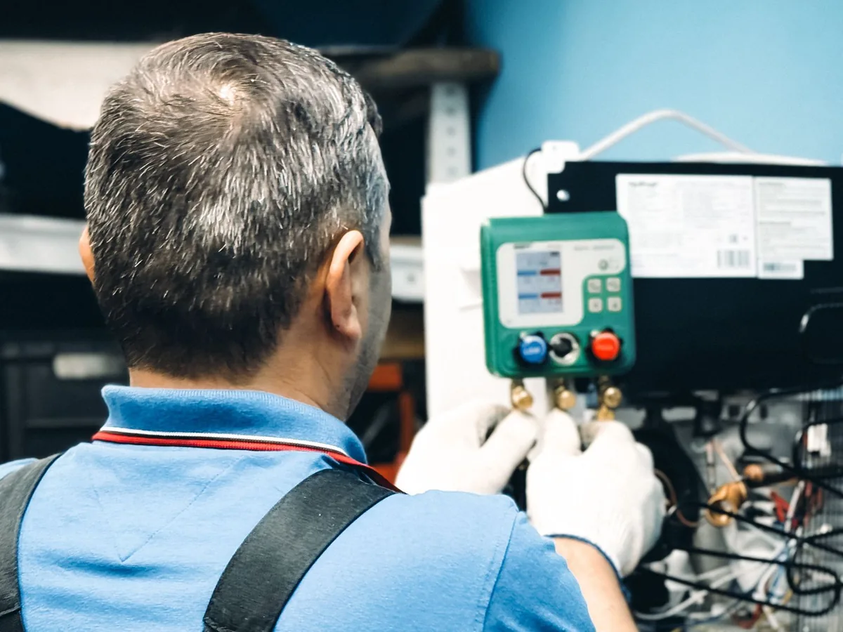 Water heater technician taking a gauge reading off an open control panel in Charlotte